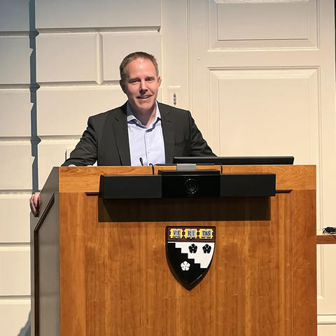 Michael smiling, standing behind a large lectern.